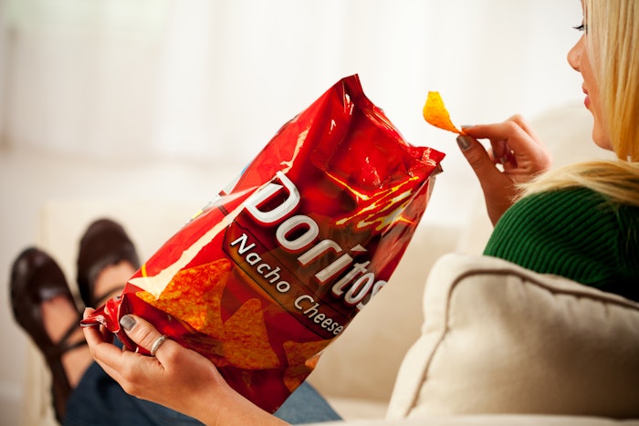 Woman Eats Chip From Bag Of Doritos