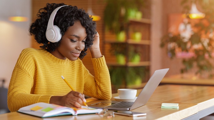 Smiling black girl with headset studying online, using laptop