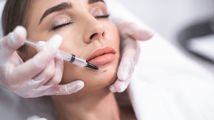 Beauty procedure. Close up portrait of attractive young lady with closed eyes and beautician arms with syringe