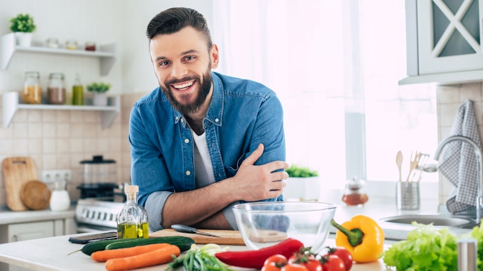 Bearded smiling handsome man in the kitchen at home is posing and looking on the camera