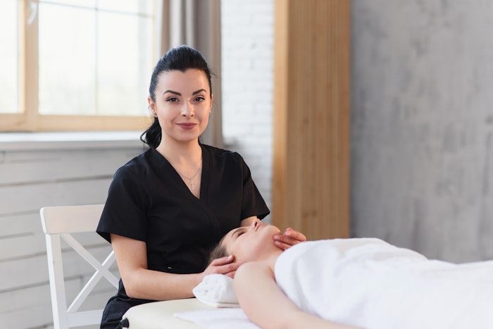 Attractive female massaeur looking to the camera on the spa background.