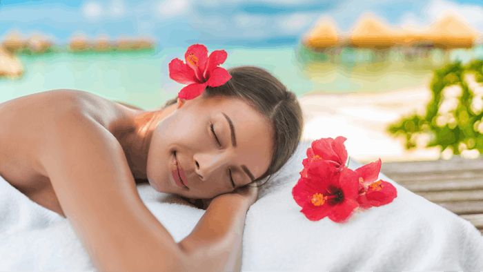 Luxury hotel spa massage table Asian woman relaxing on exotic travel vacation on beach. Summer pampering lifestyle skincare body care.