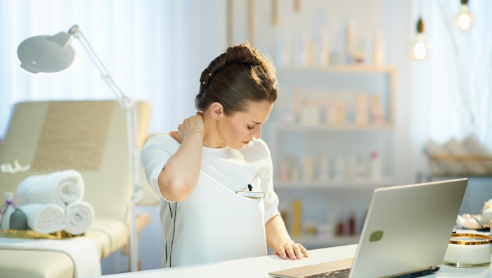 tired female employee having neck pain in modern beauty studio