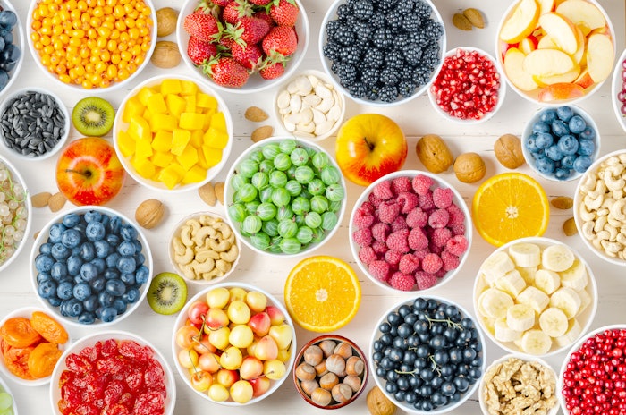 Berries, fruits and nuts on a white wooden background. Vegetarian food with flavonoids.