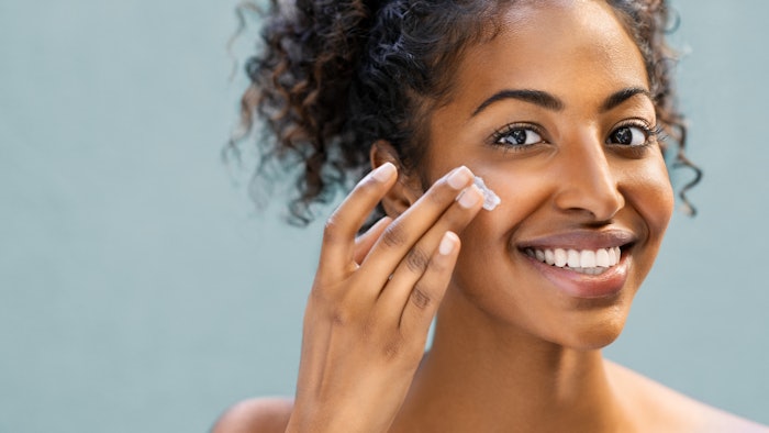 Woman applying moisturizer on face