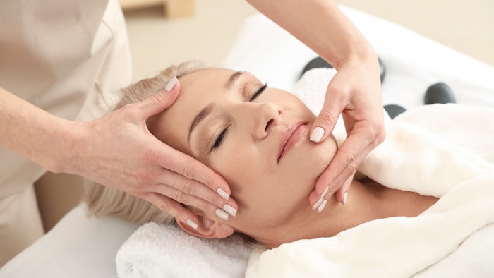Mature woman receiving face massage in wellness spa