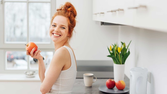 healthy-woman-redhead-eating-apple-in-white-kitchen