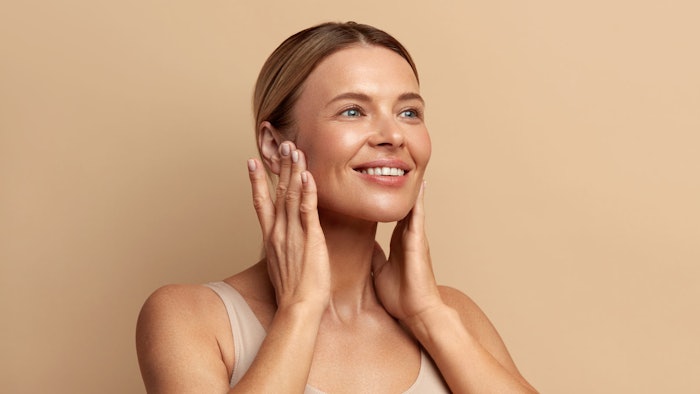 beautiful young woman skin care concept radiant hair pulled back touching face