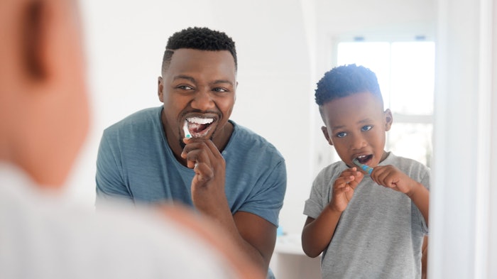 black man adult and child brushing teeth in mirror