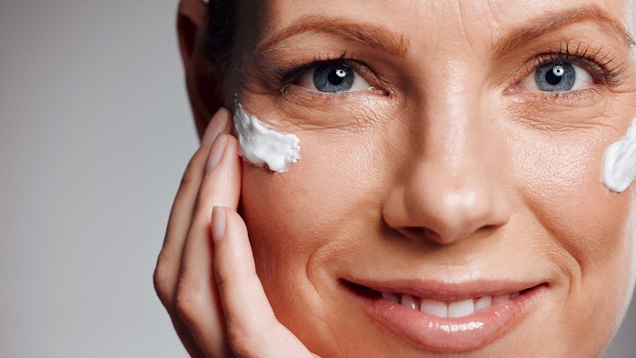 close up mature woman smiling lotion on face