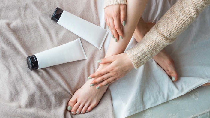 woman-legs-crossed-on-bed-tubes-of-creams