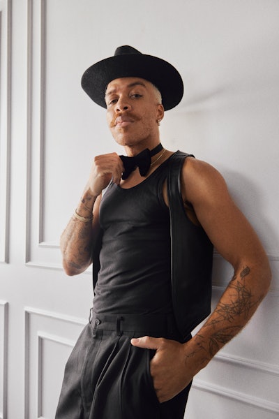 Vernon François poses for the camera in a fedora, bowtie and dressed in all black.
