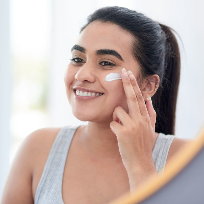 young beautiful woman smiling in mirror using product