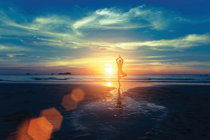 Yoga silhouette at sunset on the sea shore. Calm and self-control.