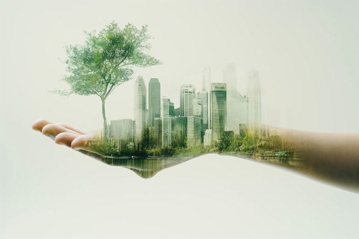 Hand holding sustainable cityscape with lush green trees