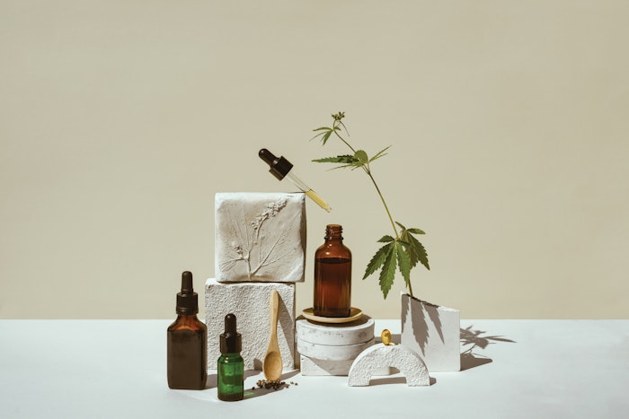 CBD oil, cannabis setting in different bottles and marijuana leaf, cannabis in a still life on geometric podium