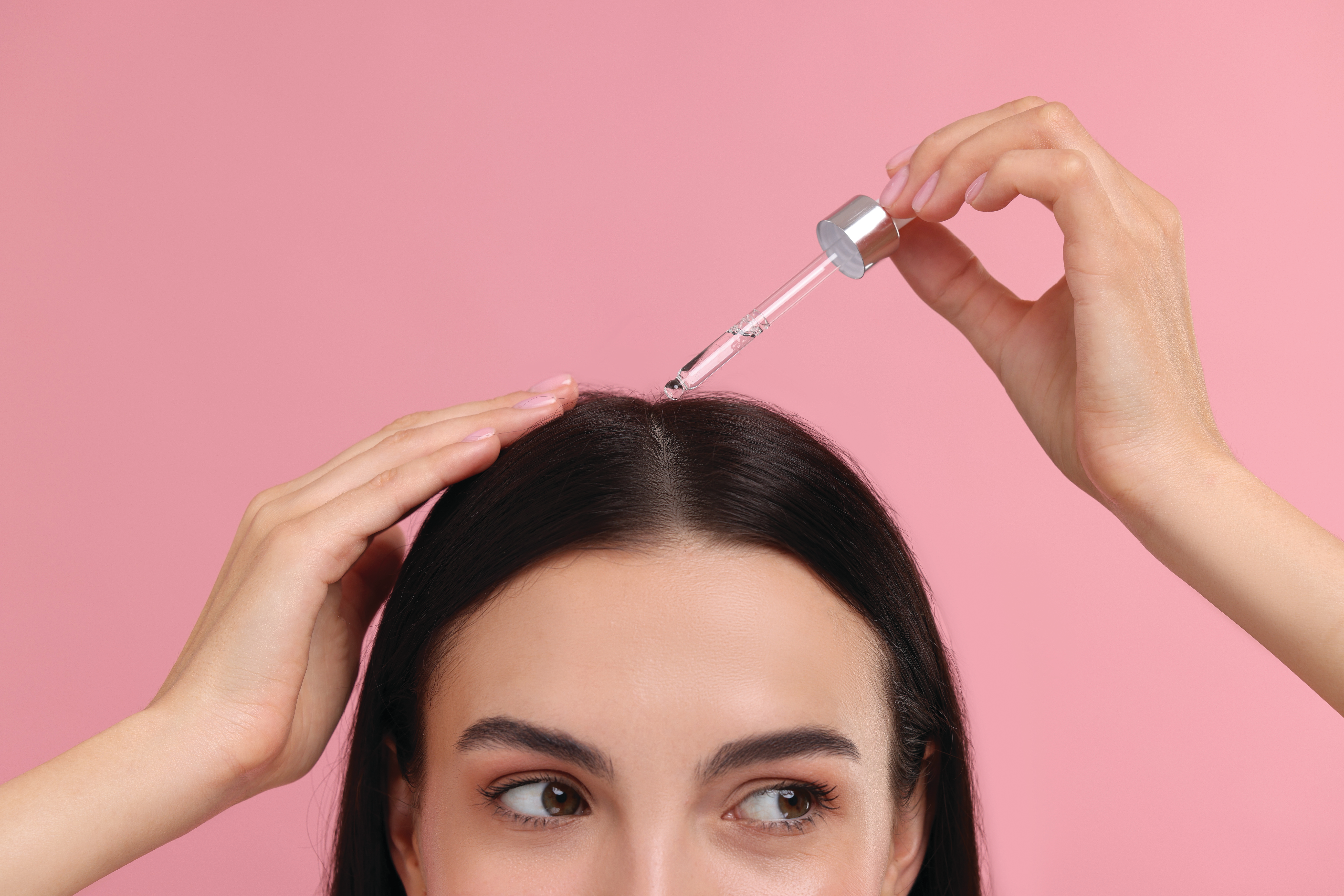 Woman applying oil to her scalp.