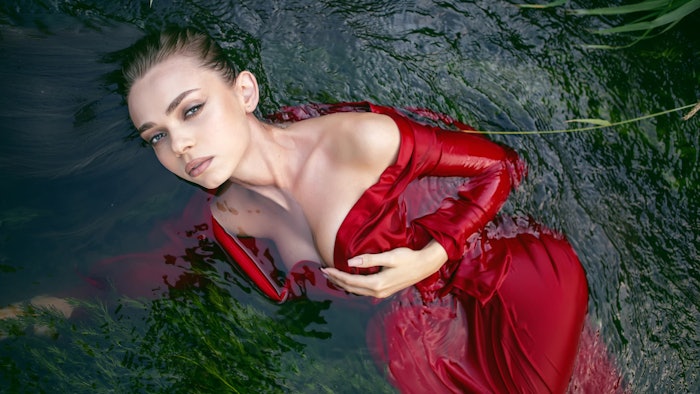woman in red dress floating in water with algae