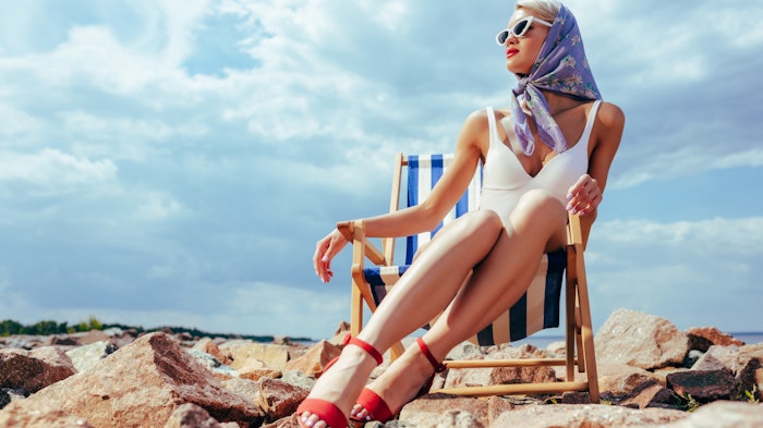 woman retro bathing suit sunglasses scarf on rocky beach