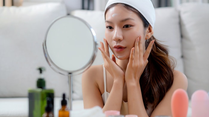 Beautiful Young Asian Woman Using Skin Care Looking In Mirror Adobe Stock 1305890064
