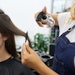 Hairstylist applying heat protectant to a section of a client's hair.