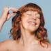 Redhead Applying Facial Serum Happy Emotion Eyes Closed Adobe Stock 540650473