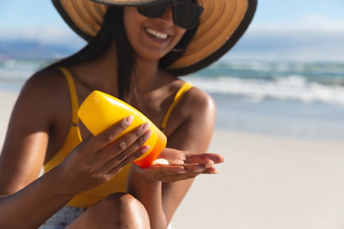 Woman On Beach With Floppy Sun Hat Applying Sunscreen Adobe Stock 426393637