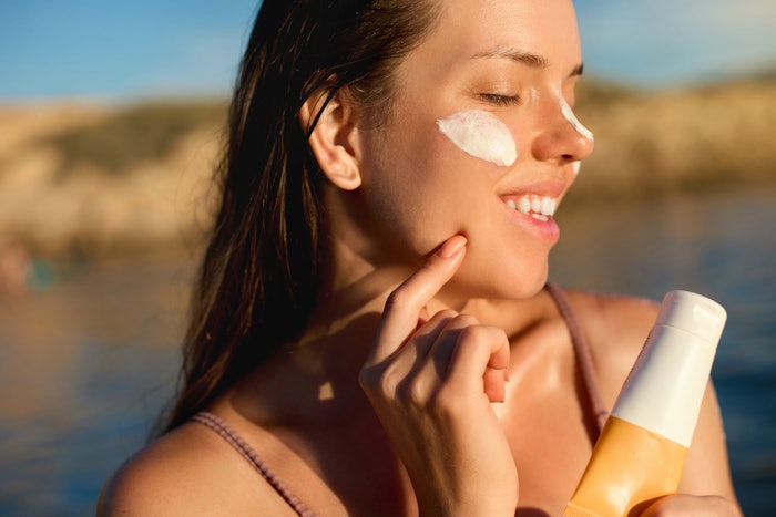 Woman Applying Sunscreen Outside Beach Sunlight Holding Product Adobe Stock 1566888505