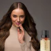 Woman with long dark hair touching her face next to Purakán essential oil bottle