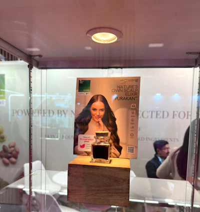 Purakani hair elixir product display in retail booth with branded poster and glass enclosure