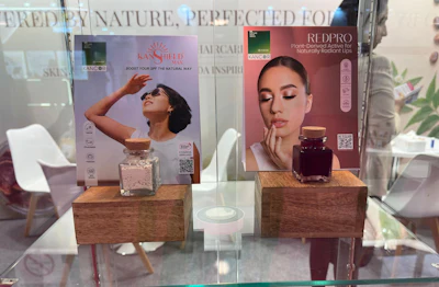 Retail beauty product display with Kans Help and RedPro branded marketing posters and glass bottles on wooden stands