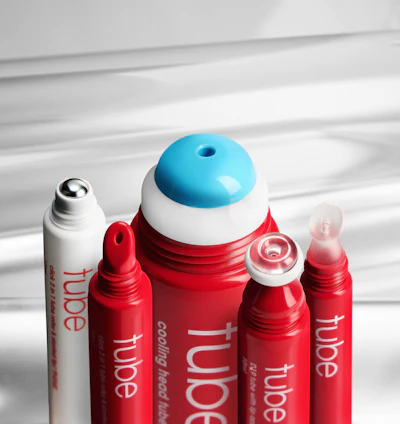 Collection of red and white cosmetic tubes with blue-capped skincare product displayed on white surface with dramatic lighting
