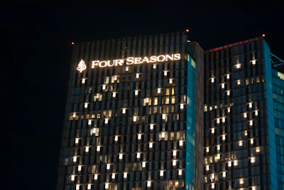 Four Seasons hotel illuminated sign on building facade at night with lit windows
