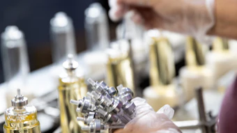 Factory workers assembling or inspecting bottled products on an industrial production line with metal components and equipment.