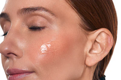 Woman's face in profile showing luminous highlighter makeup on cheekbone