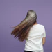 Person with long flowing hair wearing white t-shirt against purple background