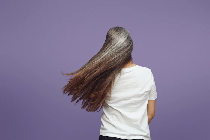 Person with long flowing hair wearing white t-shirt against purple background