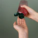 Hands dispensing red liquid from a black pump bottle against green background