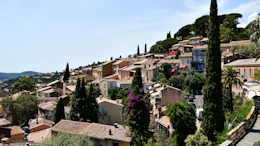 Hillside Mediterranean village with terracotta buildings, cypress trees, and colorful facades overlooking coastal landscape