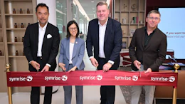 Four professionals at Symrise ribbon-cutting ceremony in modern office with shelving
