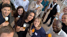 Group of diverse professionals smiling and holding drinks at a social gathering or team event