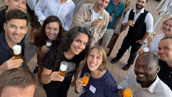 Group of diverse professionals smiling and holding drinks at a social gathering or team event