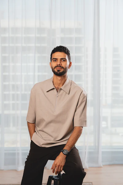 Professional man in beige polo shirt sitting in modern office with city skyline view