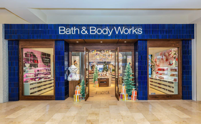 Bath & Body Works retail storefront with blue facade, illuminated signage, and holiday decorations in mall setting