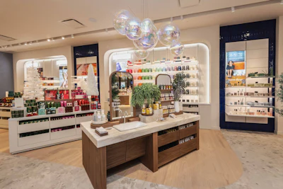 Modern beauty retail store interior with illuminated display shelves, central wooden counter, and hanging iridescent spheres