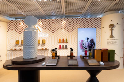 Luxury retail showroom with geometric patterned walls, product displays, and fragrance bottles on dark curved counter