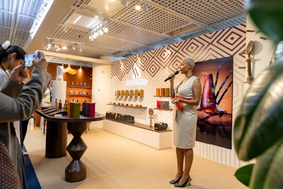 Modern retail showroom with woman presenting products on illuminated wall displays and geometric patterned backdrop