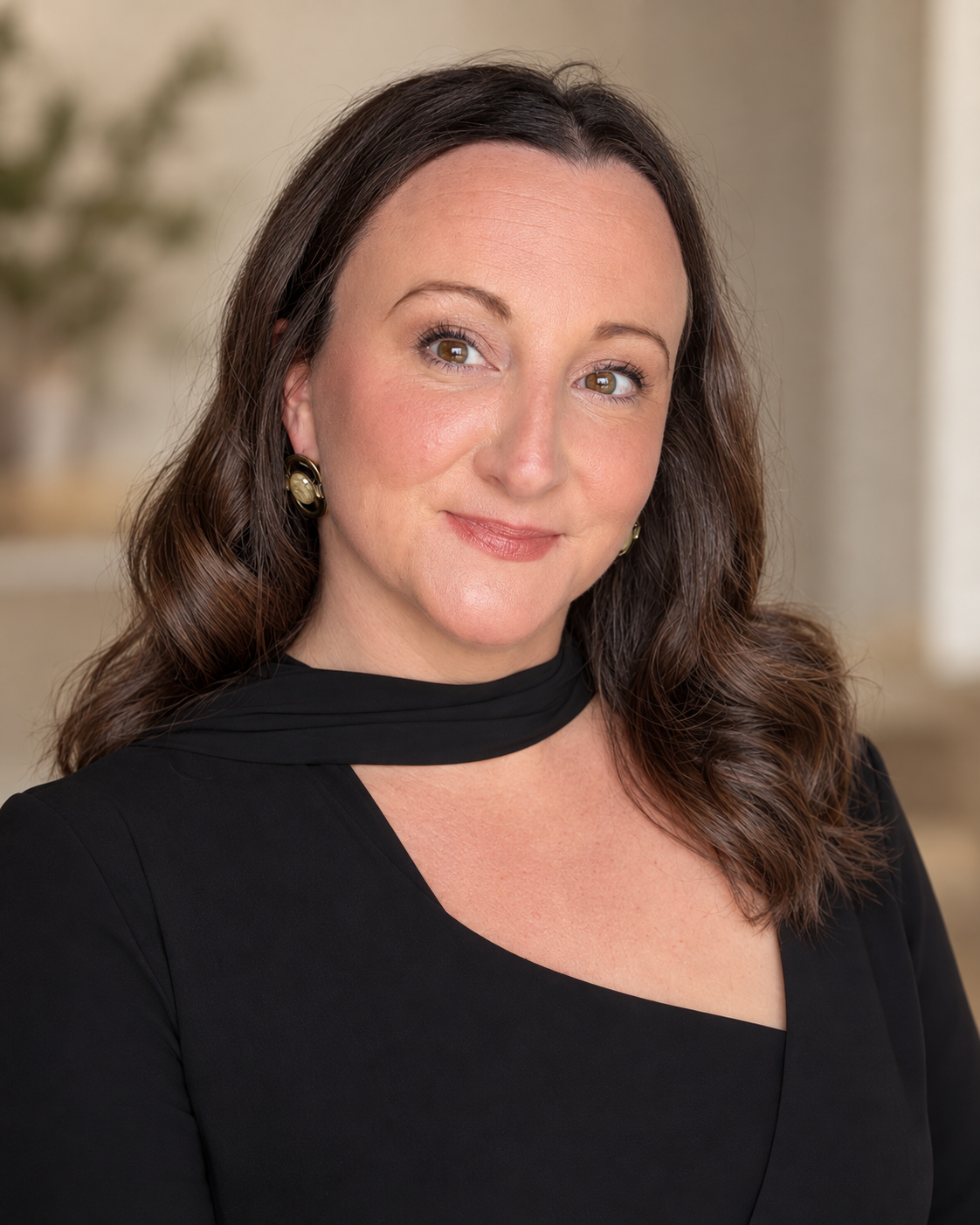 Professional headshot of a woman with long dark hair wearing a black choker-style top