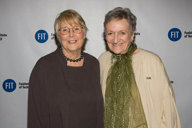 Two women smiling at Fashion Institute of Technology event with FIT logos on backdrop