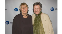 Two women smiling at Fashion Institute of Technology event with FIT logos on backdrop
